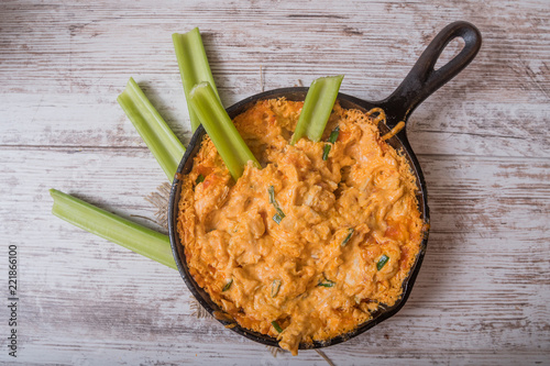 Flat lay of baked cheese dip in skillet with celery