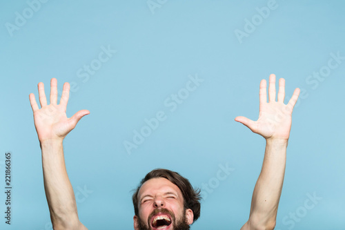 happiness enjoyment and laugh. excited man with hands in the air. portrait of a young bearded guy on blue background. emotion facial expression. feelings and people reaction. photo