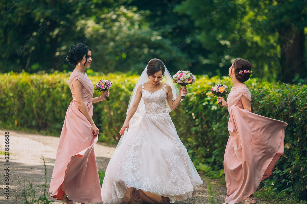 Bride and bridesmaid in nature with bouquets of flowers. Funny wedding