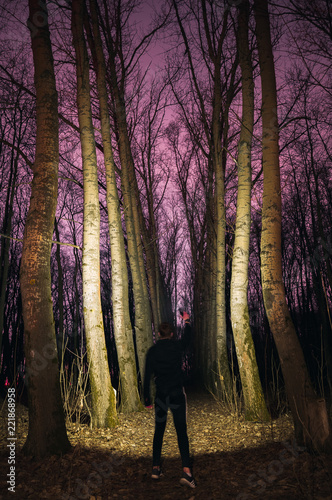 A man with a flashlight at night in a dark forest