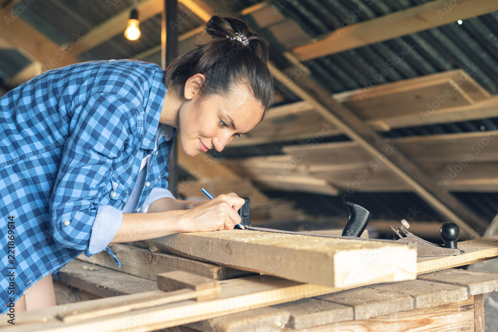 Side view of a woman carpenter draws on a wooden Board cut line Side view of a woman carpenter draws on a wooden Board cut line