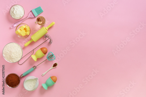 Butter, sugar, flour, eggs, oil, spoon, rolling pin, brush, whisk, towel over pink background. Bakery food frame, cooking concept. Ingredients on kitchen table. Top view, copy space. Flat lay © jchizhe