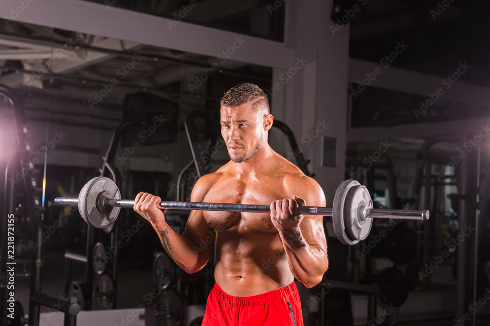 Bodybuilder doing the exercises with barbell. Strong male with naked torso on dark background. Strength and motivation. Bodybuilder doing the exercises with barbell. Strong male with naked torso on dark background. Strength and motivation.
