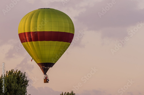 Colorful hot-air balloon flies over typical village in the Tuscan countryside in the light of the sunset