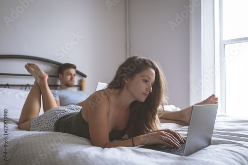 Couple using laptop and digital tablet in bedroom photo