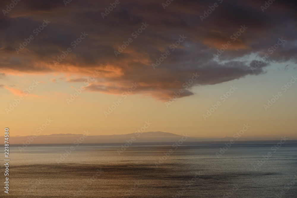 Dark cloud over ocean in afterglow between islands of Canary.