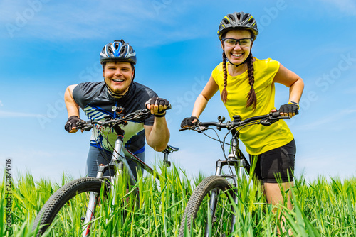young smiling strong man and woman standing at green field with
