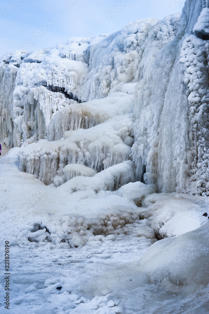 A frozen waterfall with ice in blue and white color in winter. Winter background. Jagala Waterfall, Estonia. A frozen waterfall with ice in blue and white color in winter. Winter background. Jagala Waterfall, Estonia.