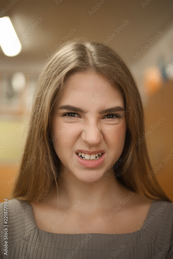 Angry young student schoolgirl lady with long hair in empty classroom looking camera showing emotions grimace. Angry young student schoolgirl lady with long hair in empty classroom looking camera showing emotions grimace.