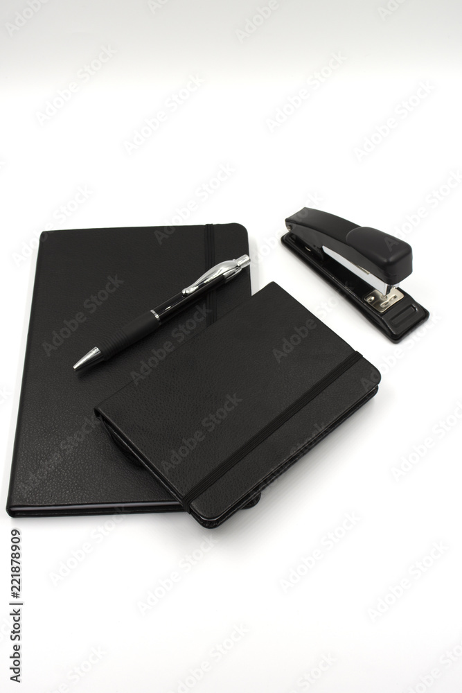Conjunto de libreta, bolígrafo, móvil y grapadora de color negro en fondo blanco. Oficina Conjunto de libreta, bolígrafo, móvil y grapadora de color negro en fondo blanco. Oficina
