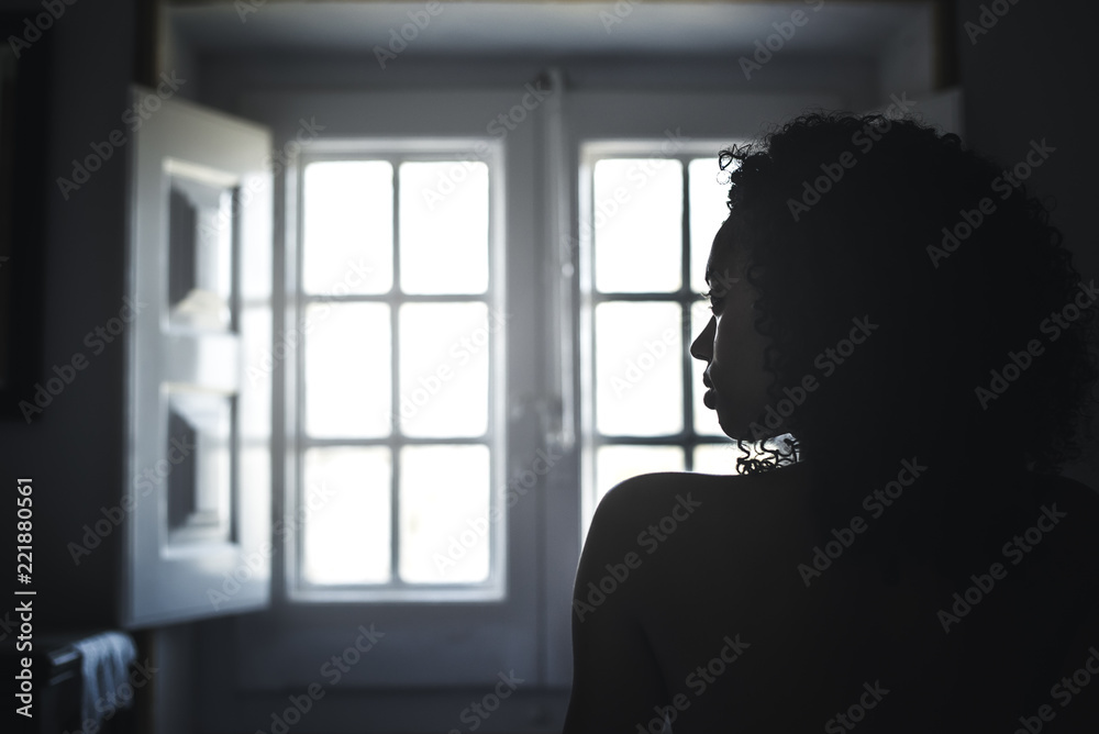 Woman wrapped in a towel looking by a vintage window.