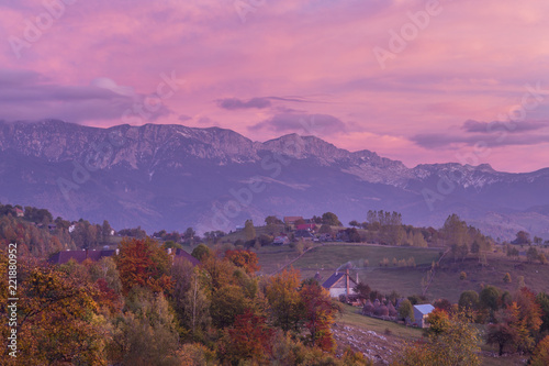 Autumn alpine landscape, alpine village with spectacular gardens and high snowy mountains in background near Bran, Magura, Transylvania, Romania.