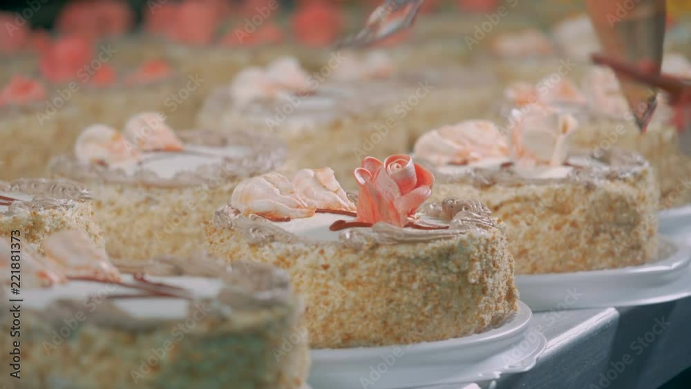 Worker decorates cakes with roses, close up. Worker decorates cakes with roses, close up.