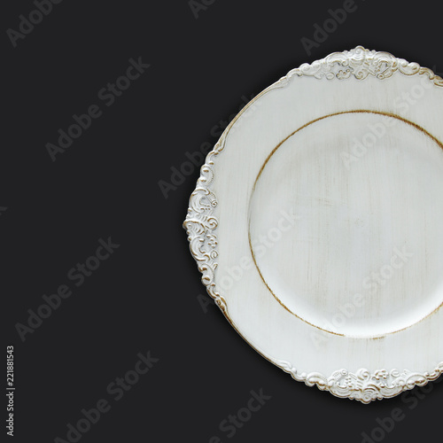 Top view of vintage white empty plate over black background. Flat lay.