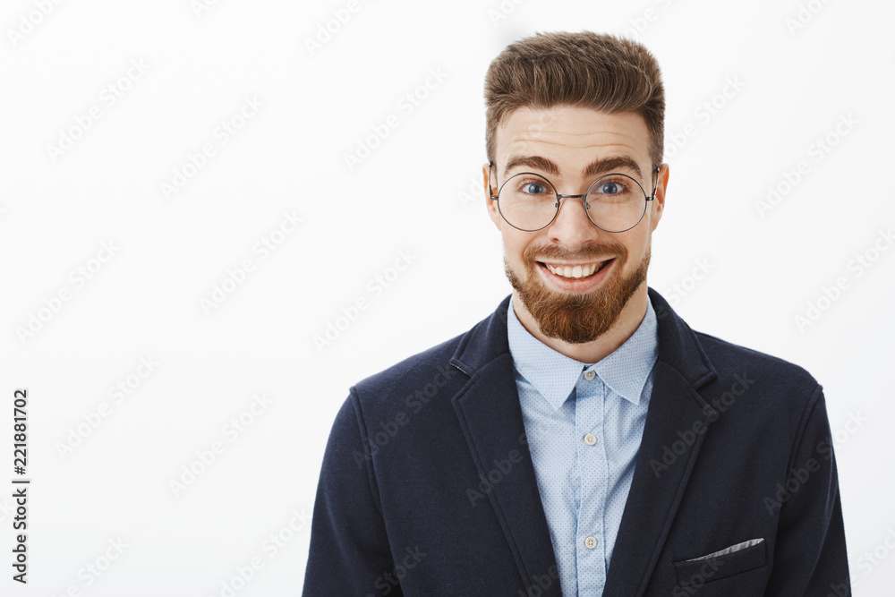 Ambitious smart and creative stylish young businessman in round glasses with beard and blue eyes standing in trendy suit smiling broadly feeling amazed and excited starting new project Ambitious smart and creative stylish young businessman in round glasses with beard and blue eyes standing in trendy suit smiling broadly feeling amazed and excited starting new project