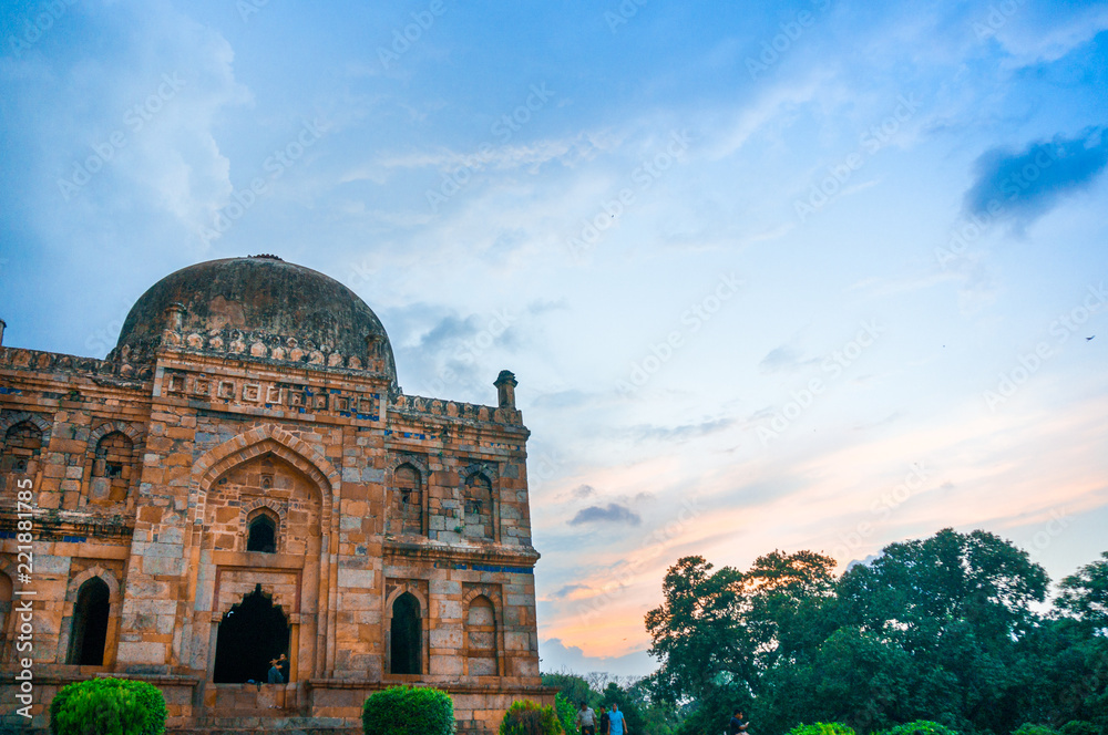 Stone dome at lodhi garden in delhi on a sunset evening with colorful clouds in pink, blue and white. This park filled with Mughal architecture is a popular spot for locals and tourists