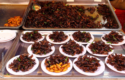 Portions of fried crickets or cockroaches on the counter of a market trader. Traditional asian street cooking © Вера Тихонова