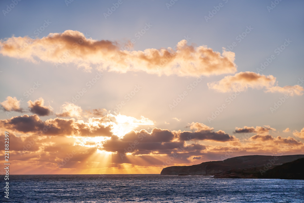 Beautiful sunset with God rays over Mediterranean sea. Gozo island, Malta.