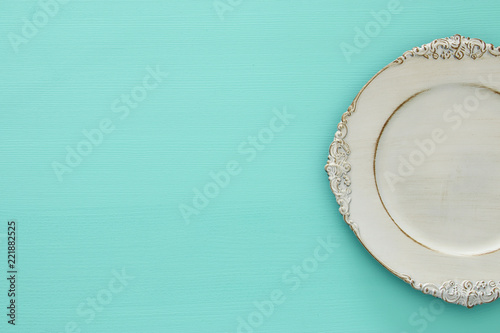 Top view of vintage white empty plate over blue mint wooden background. Flat lay