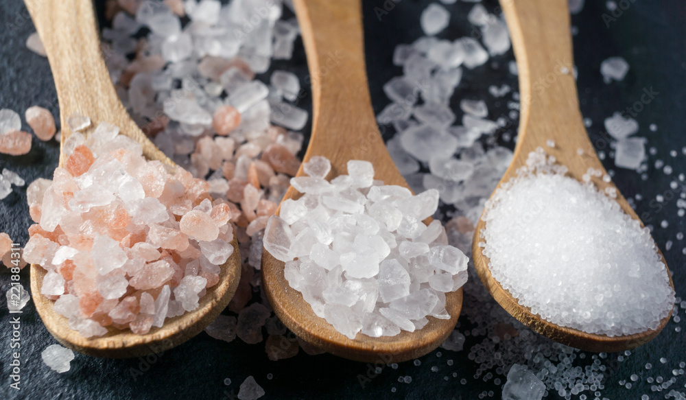 Different types of salt. Top view on three wooden spoons