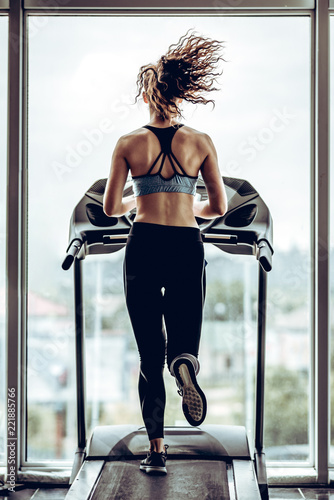 Bild auf Leinwand Beautiful attractive woman runs on the running track