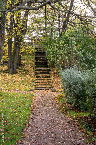 The old staircase leads up in the autumn park. Steps with autumn leaves. Autumn landscape