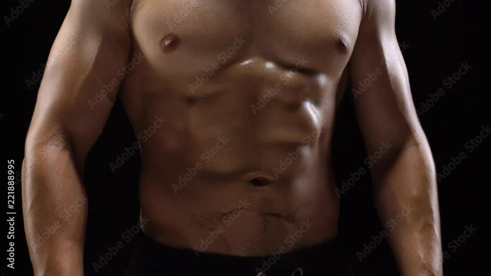 Man shows a muscular strong body close-up on a black background Man shows a muscular strong body close-up on a black background