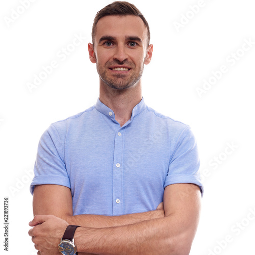 Casually handsome. Confident young handsome man in jeans shirt keeping arms crossed and smiling while standing against white background