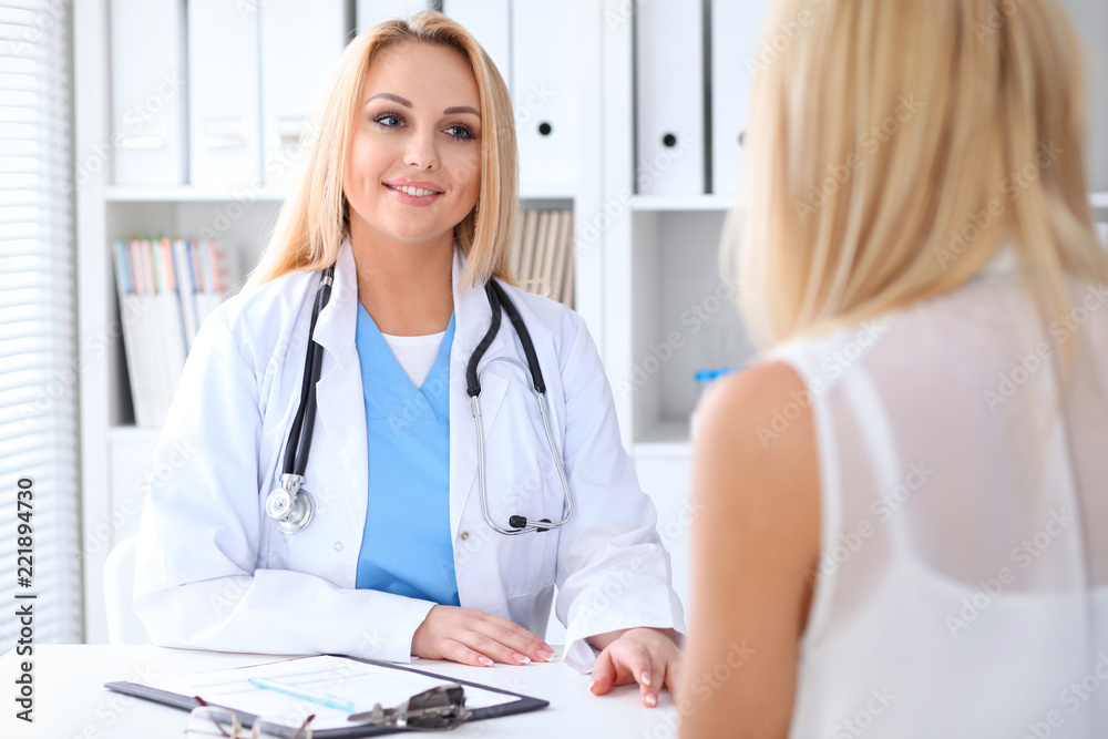 Doctor and patient discussing something while sitting at the table at hospital. Medicine and health care concept Doctor and patient discussing something while sitting at the table at hospital. Medicine and health care concept