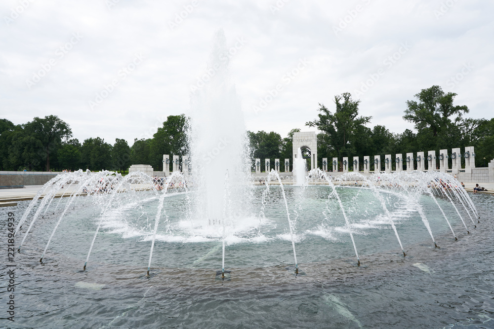 Water fountain at WWII memorial in Washington DC with tourists around the edge.