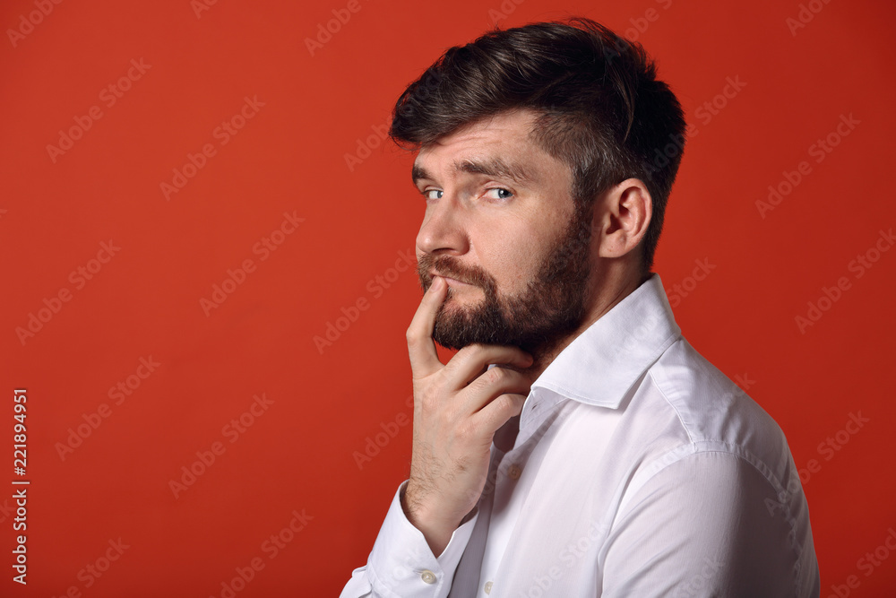 Thinking bearded charismatic man in profile view in whirt shirt looking on bright orange background. Closeup portrait Thinking bearded charismatic man in profile view in whirt shirt looking on bright orange background. Closeup portrait
