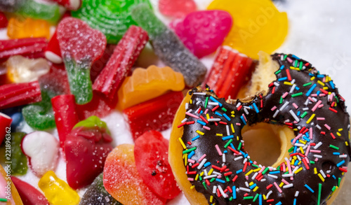 Mix of tempting sweet cakes, donuts and candy with sugar spread in unhealthy nutrition, chocolate abuse and sugar addiction concept, body and dental care and health problems..
