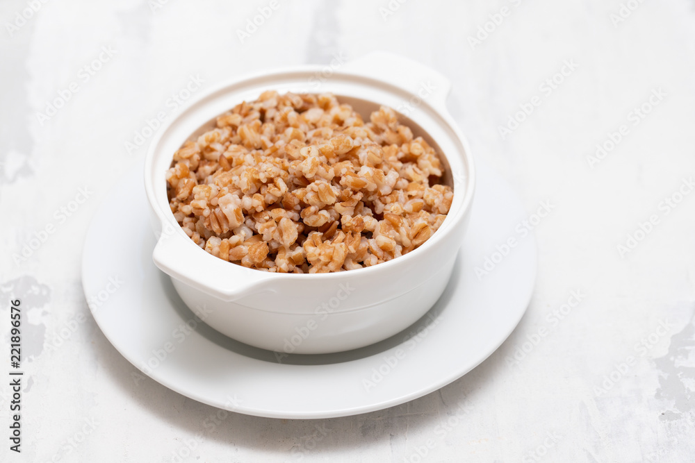 boiled spelt in white bowl on ceramic bckground boiled spelt in white bowl on ceramic bckground
