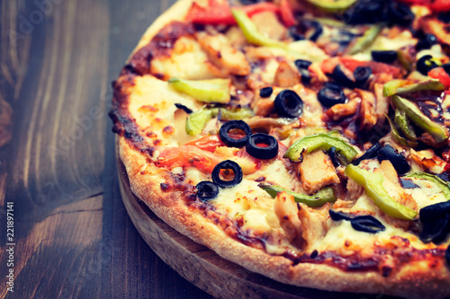 pizza with chicken and olives on brown wooden background