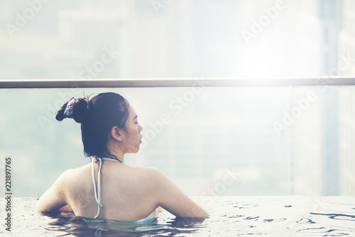 Photography Young woman in a roof top swimming pool with beautiful city view, sunlight vinta
