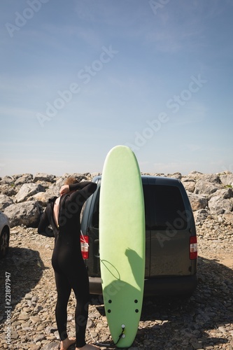 Surfer wearing wetsuit near beach photo