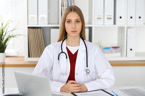 Brunette female doctor using laptop computer in hospital. Healthcare, insurance and medicine concept