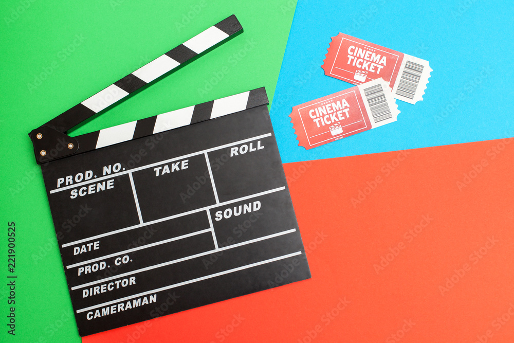 A view from above of movie tickets and a movie clapper on a bright green-blue-red background with space for text. Movie time concept, Flat lay, Cinema background. Film watching