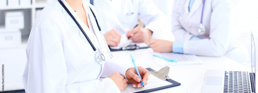 Group of unknown doctors working at hospital while sitting at the table. Teamwork and success concept in medicine Group of unknown doctors working at hospital while sitting at the table. Teamwork and success concept in medicine