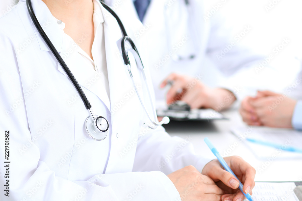 Group of unknown doctors working at hospital while sitting at the table. Teamwork and success concept in medicine Group of unknown doctors working at hospital while sitting at the table. Teamwork and success concept in medicine
