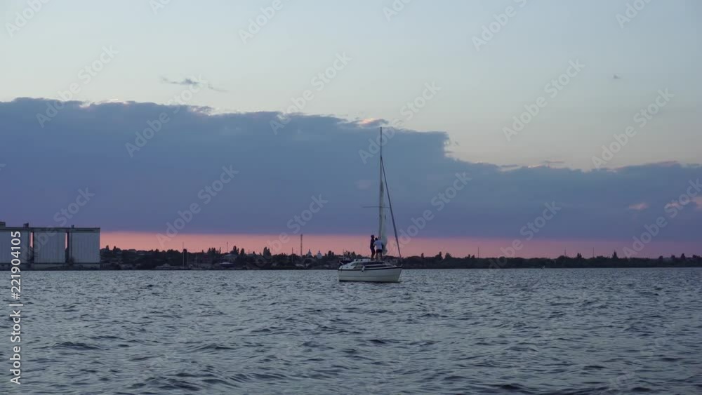 White small boat yacht sailing slowly in calm river waves in impressive warm evening sunset panorama low angle seascape White small boat yacht sailing slowly in calm river waves in impressive warm evening sunset panorama low angle seascape