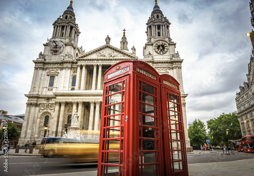 red phone boxes and yellow car passing Saint Paul s Cathedral in London at cloudy day