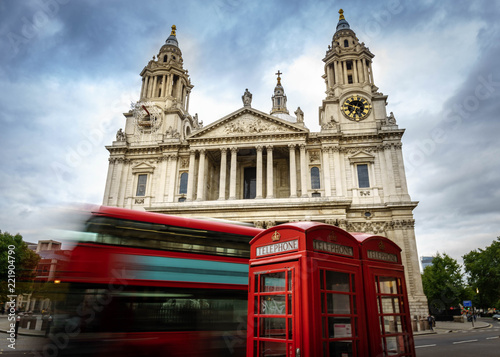 red phone boxes and red bus passing Saint Paul's Cathedral in London at cloudy day