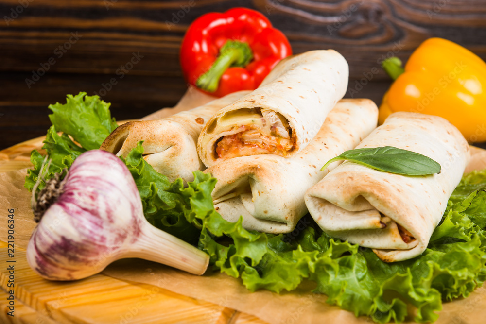 Double burrito with chicken in Caesar sauce on a dark wooden background