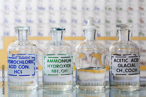 Four reagent bottles containing hydrochloric acid, ammonium hydroxide, water and acetic acid.