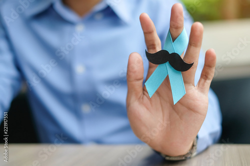 Prostate Cancer Awareness, Man hand holding light Blue Ribbon with mustache for supporting people living and illness. Men Healthcare and World cancer day concept photo