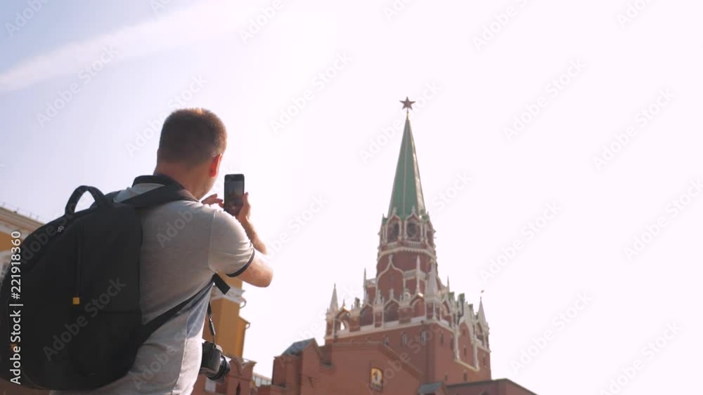 Travel and technology lifestyle. Happy tourist man looks the navigator smartphone taking selfie with backpack. slow motion video. on Red Square in Moscow, Russia. tourist journey travel man in Russia