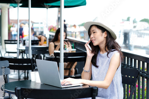 Young asian woman talking phone while working at cafe in the city outdoors background, people working outdoors with technology, lifestyle