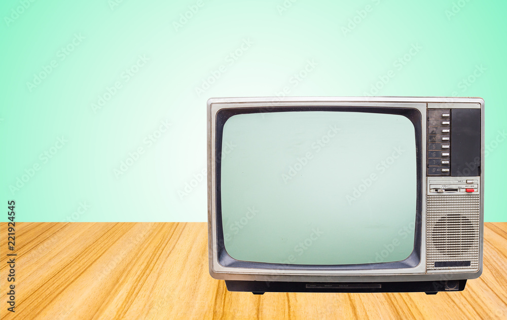 Retro old television receiver on beside table front gradient green wall background.