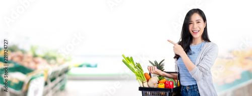 Woman with shopping basket full of groceries in supermarket banner background